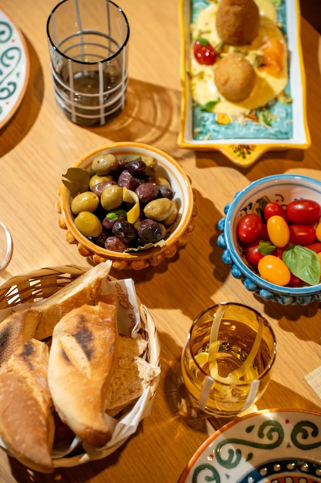 Olives, cherry tomatoes and bread laid out on the table
