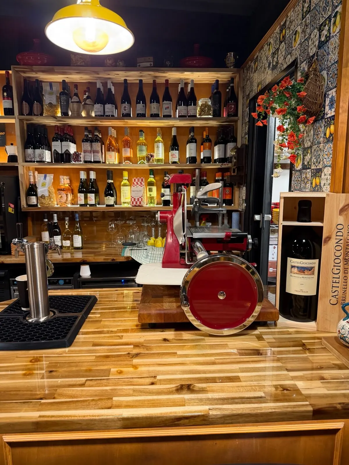 The bar — wine on the shelves, the slicer, the tiled wall