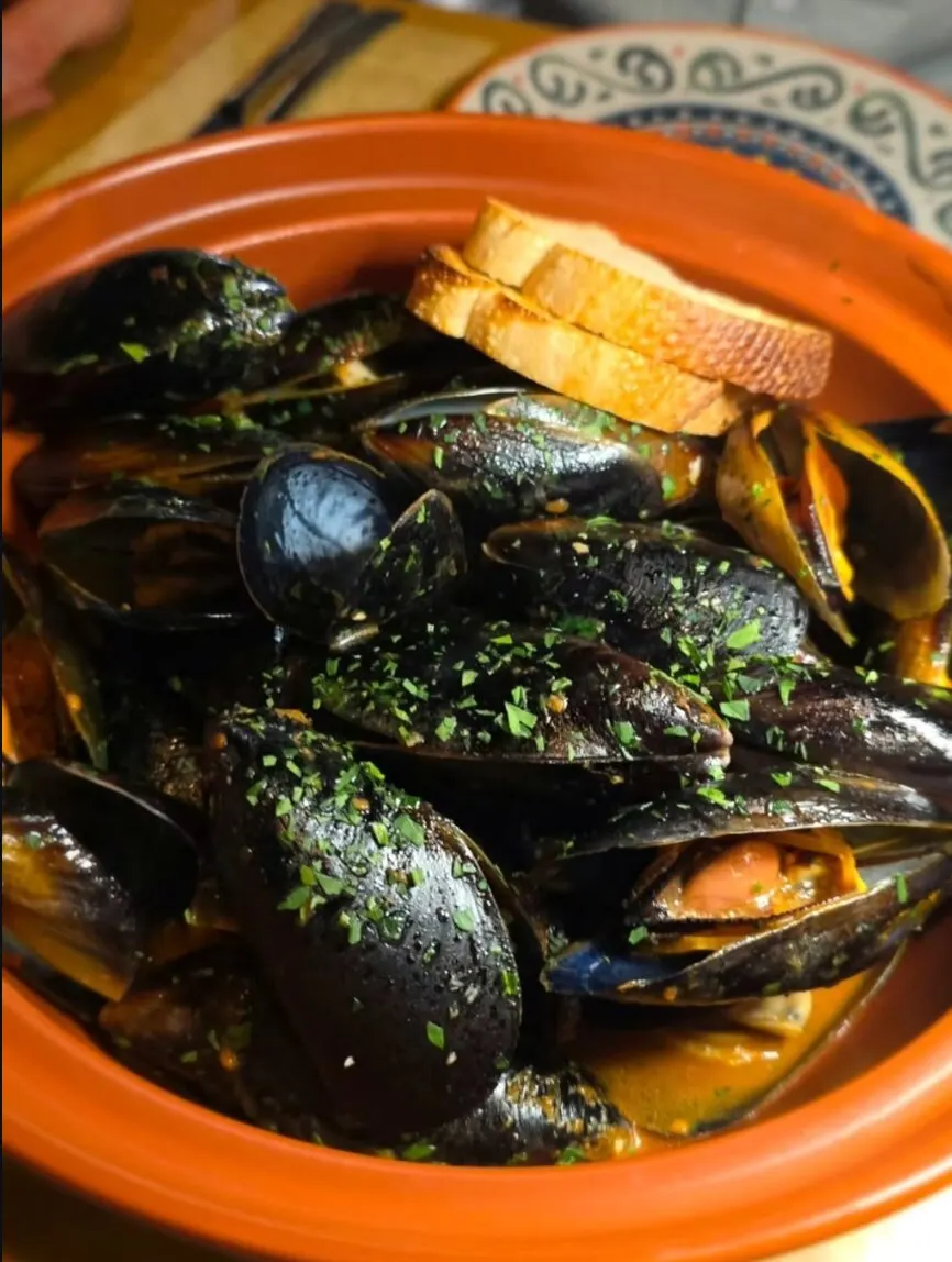 Mussels siciliana in a terracotta bowl with toasted bread