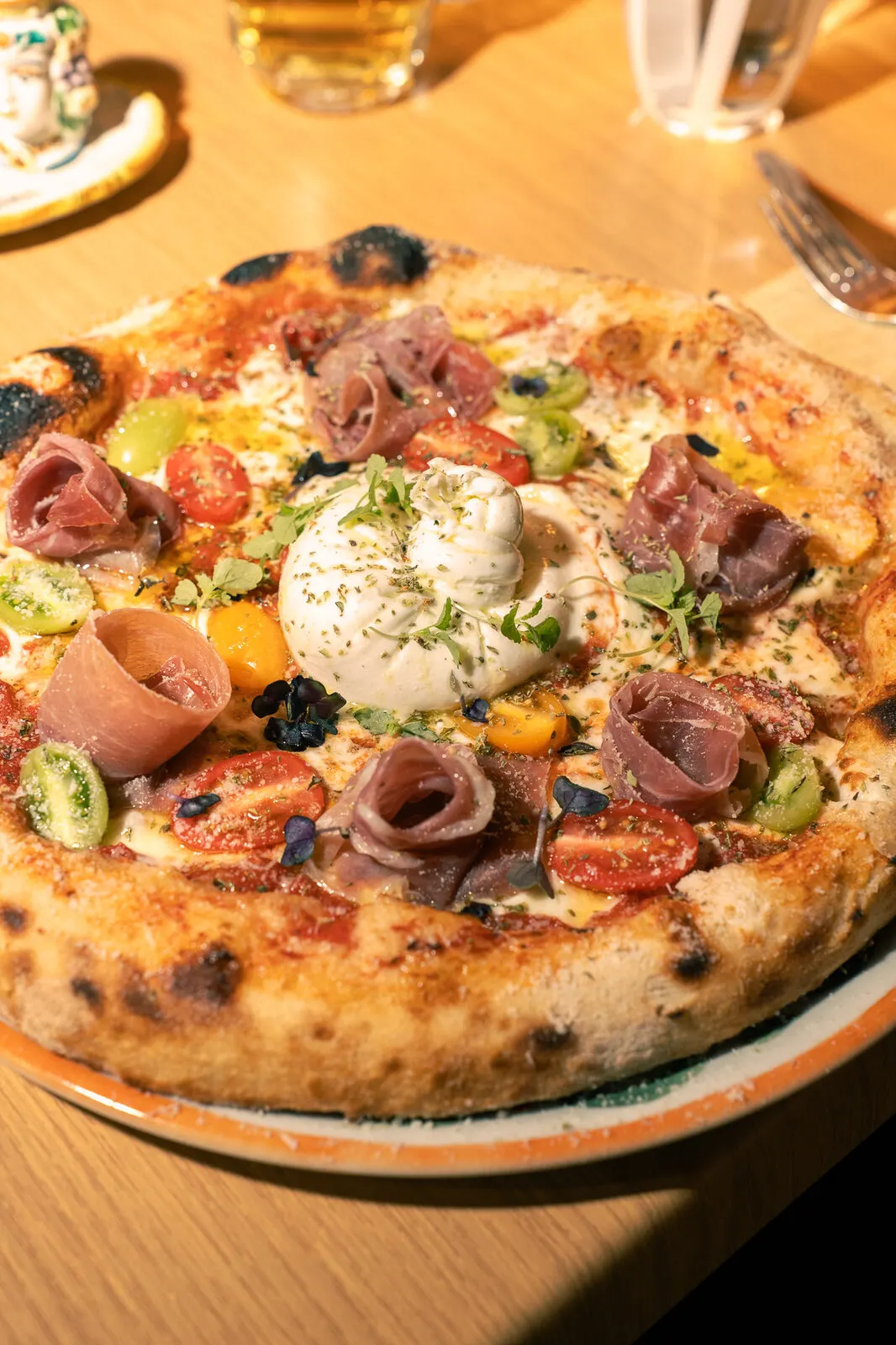 A pizza with prosciutto, burrata and cherry tomatoes