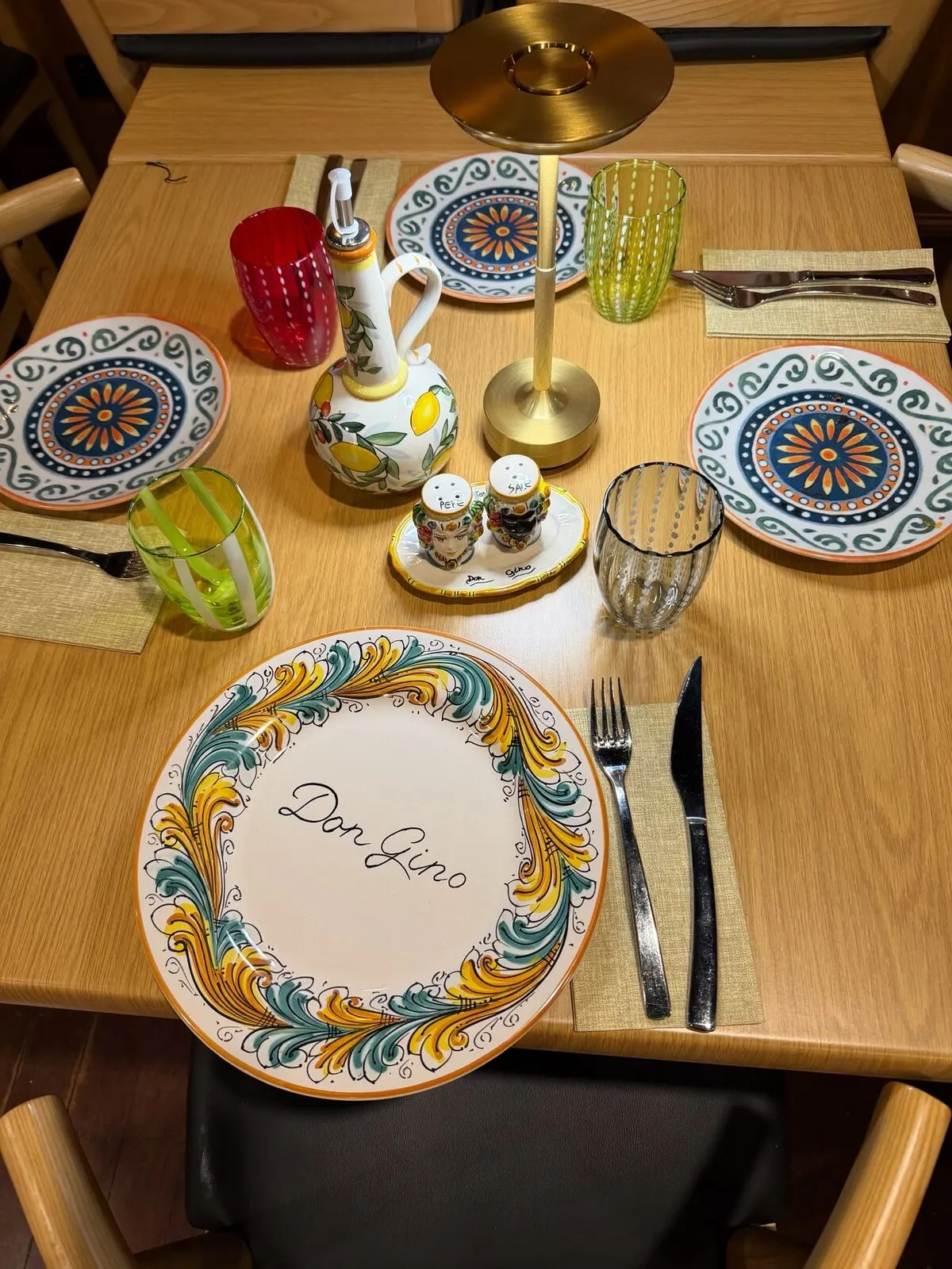 A table laid with painted Sicilian plates and an oil bottle